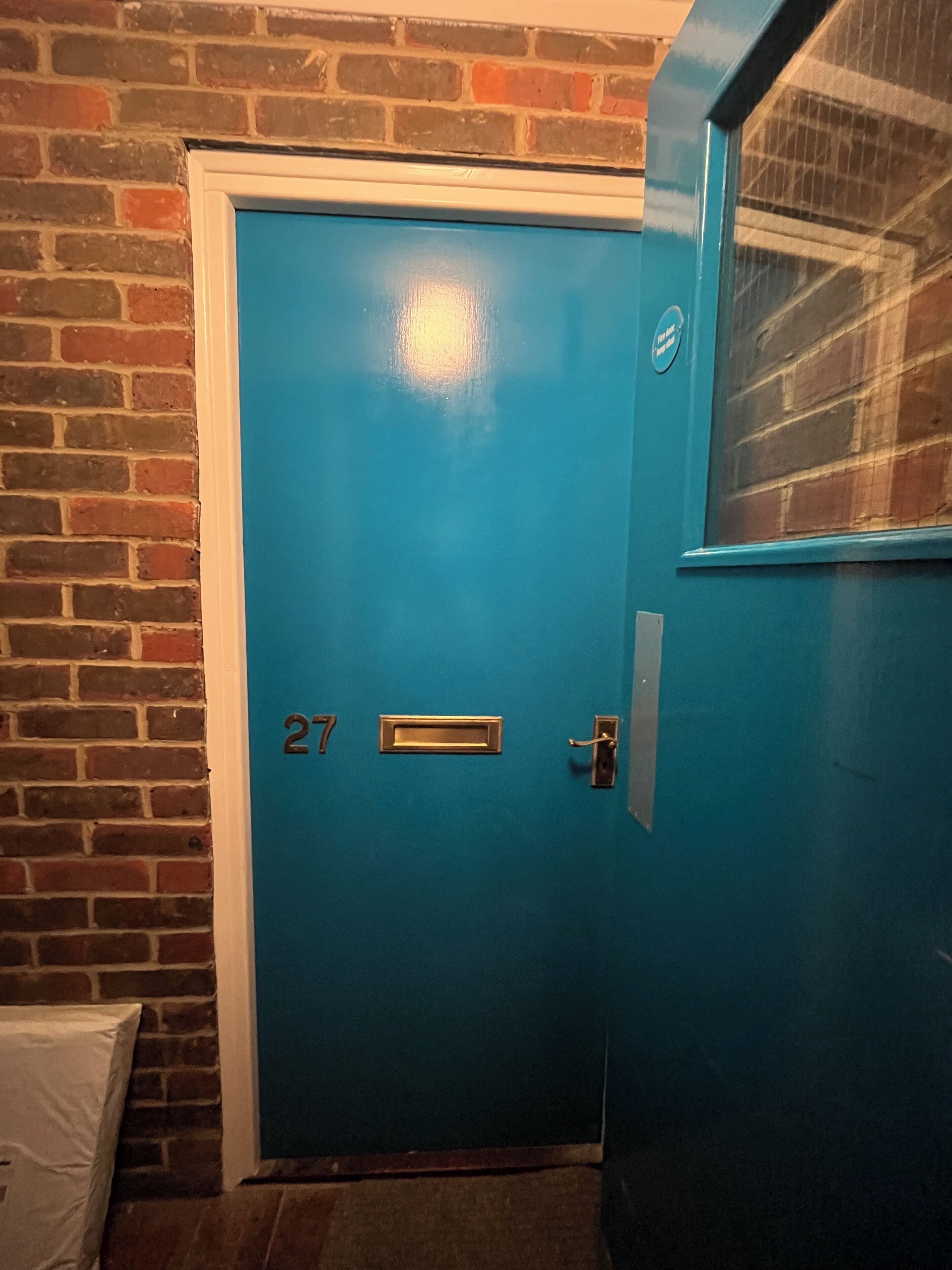 Una porta blu con il numero 27, una maniglia metallica e una serratura.