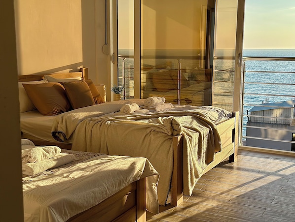 Un dormitorio con una cama grande, una mesita de noche y vistas al mar a través de un ventanal.