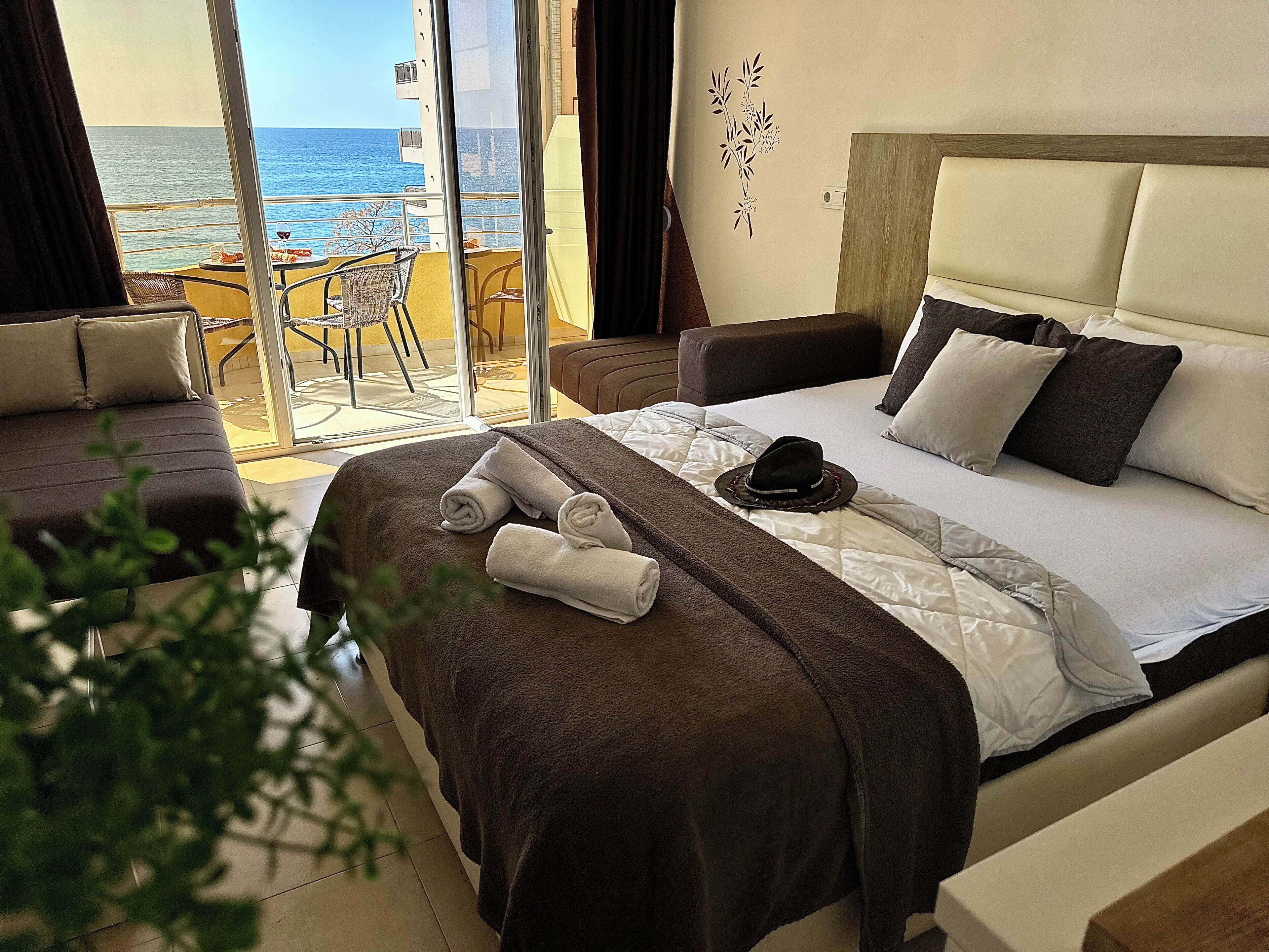 Habitación de hotel con cama, una silla, una mesa con una bebida y vistas al mar.