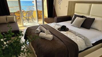 Habitación de hotel con cama, una silla, una mesa con una bebida y vistas al mar.