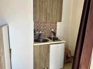 A compact kitchen with a sink, a small stove, and a refrigerator. - Apart-Hotel Saraj (Dobra Voda)