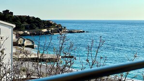 A coastal view with a stone pier, buildings, and a clear blue sea. - Apart-Hotel Saraj (Dobra Voda)