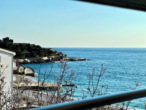 A coastal view with a stone pier, buildings, and a clear blue sea. - Apart-Hotel Saraj (Dobra Voda)