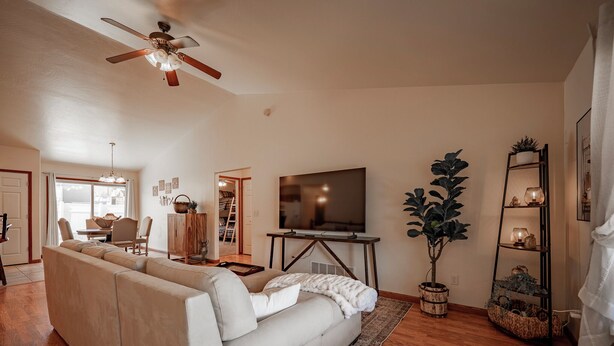 Ein Wohnzimmer mit einer Couch, Fernseher, Deckenventilator und einer Pflanze.