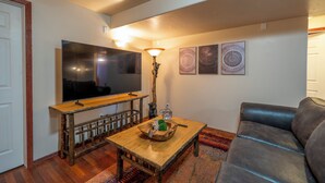 Ein Wohnzimmer mit Flachbildfernseher, Holztisch und grauem Sofa.