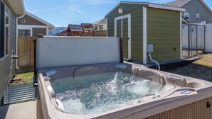 Ein Garten mit Whirlpool, einer Holzterrasse und einem kleinen Schuppen.