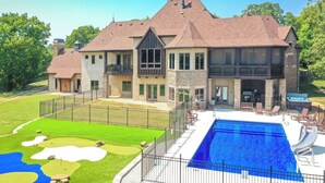 Ein großes Haus mit Swimmingpool, Terrasse und Golfplatz.