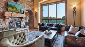 Una sala de estar acogedora con chimenea, sofás de cuero y un amplio ventanal con vistas panorámicas.