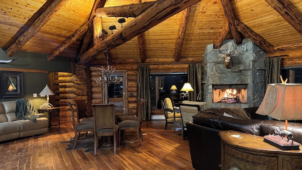 A log cabin interior with a stone fireplace, wooden floors, and a high ceiling. - Charming 3 bedroom Log cabin with WiFi in Kalispell (Kalispell)