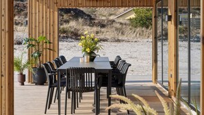 A wooden deck with a table and chairs, overlooking a beach. - 5 Star Holiday Home in Henne (Henne)