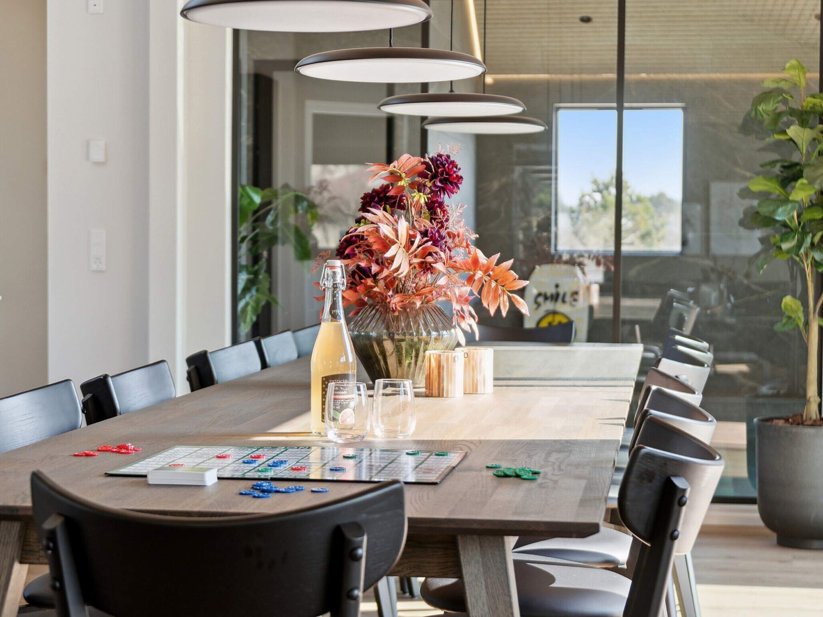 A conference room with a long table, chairs, a vase of flowers, a bottle of champagne, and a menu.