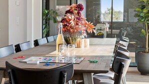 A conference room with a long table, chairs, a vase of flowers, a bottle of champagne, and a menu. - 5 Star Holiday Home in Henne (Henne)