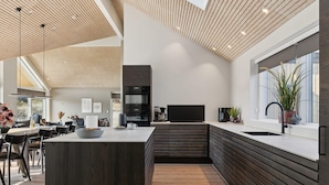 A modern kitchen with a central island, built-in appliances, and a large window. - 5 Star Holiday Home in Henne (Henne)