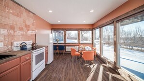Une cuisine équipée d’une cuisinière, d’un réfrigérateur et d’un coin repas avec des chaises orange.