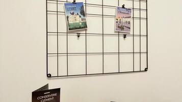 A bulletin board with two postcards pinned on it, and a brochure on a table.