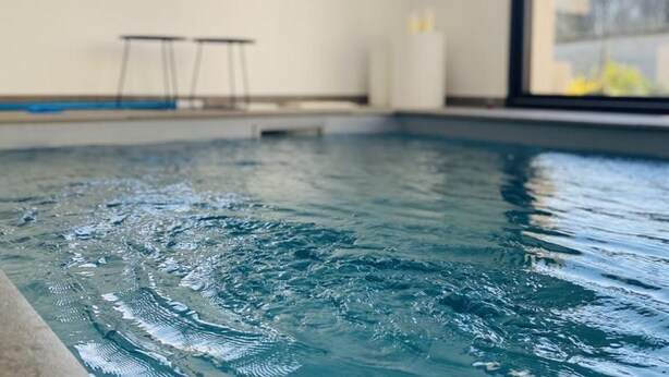 An indoor swimming pool with clear water, a window, and a white pillar. - Luxury cottage with heated pool and SPA in the heart of the Loire Valley (Ballan-Miré)
