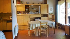 Une cuisine chaleureuse avec des meubles en bois, une table à manger entourée de chaises et une fenêtre agrémentée de rideaux.