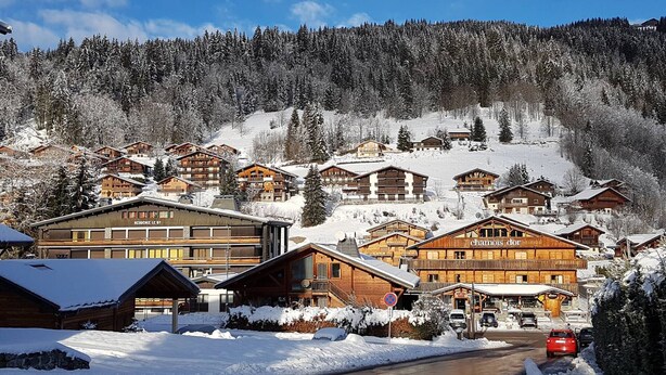 Un village de montagne enneigé, avec des chalets en bois et une station de ski.