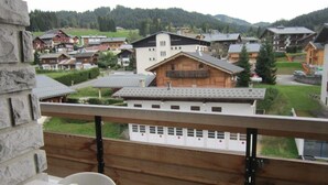 Un balcon offrant une vue sur un village, des bâtiments en bois et un paysage verdoyant.