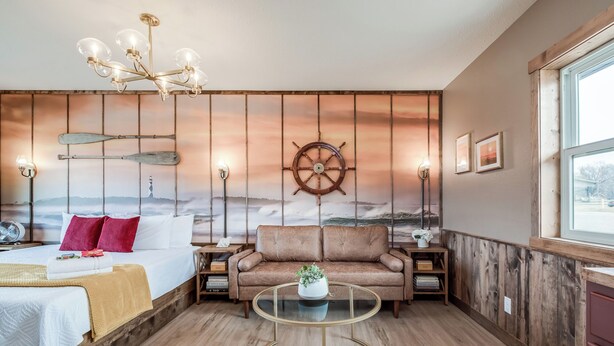 A cozy room with a bed, a sofa, a round coffee table, and a wall mural.