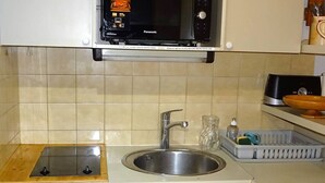 Una cuina amb microones, rentaplatets i una pica.