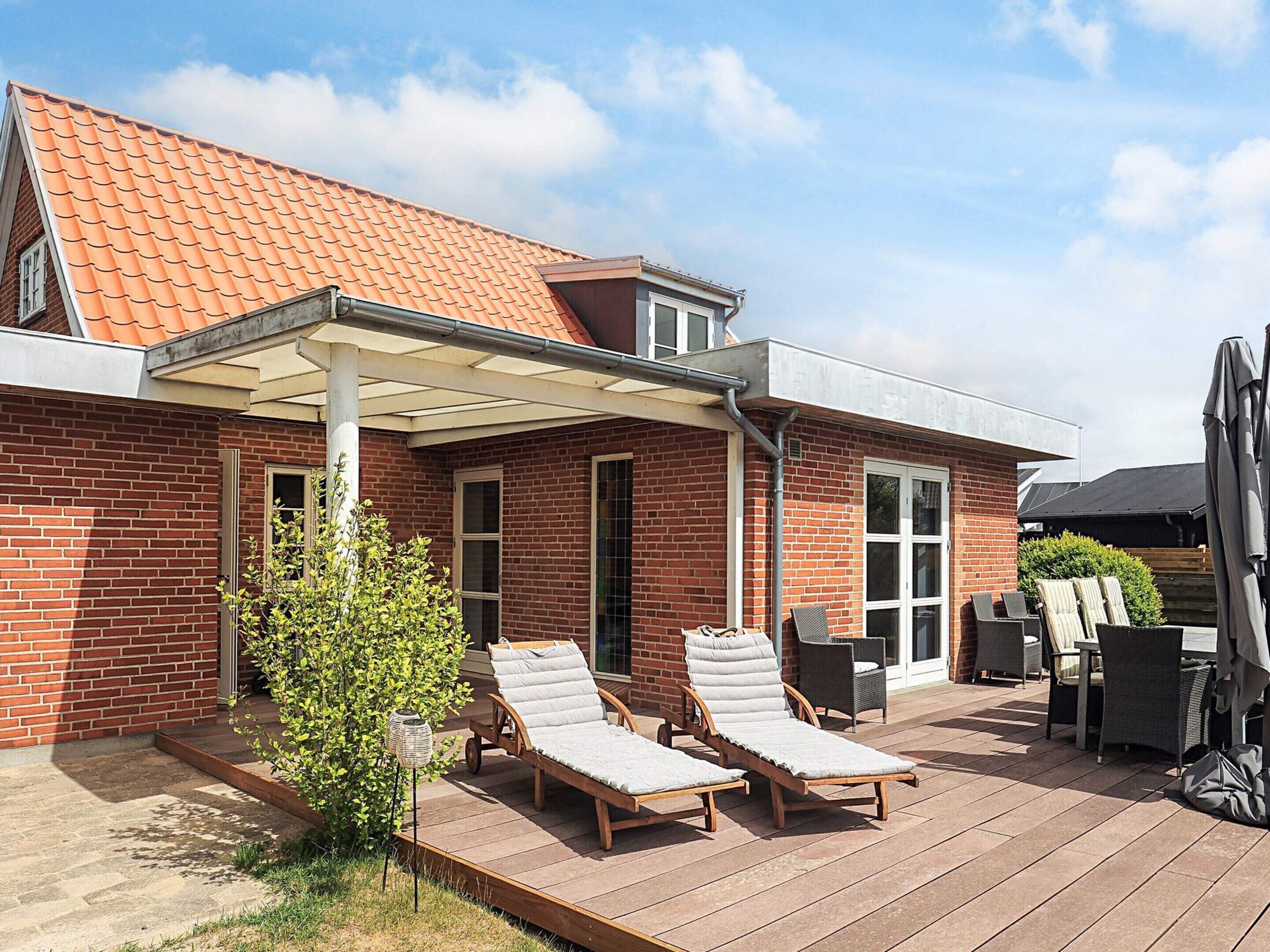 Une terrasse avec deux chaises longues, un petit arbre et une pergola.