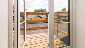 A view from a window with wooden deck flooring, overlooking a residential area with houses and a clear sky. - 4 Star Holiday Home in Vaeggerlose (Vaeggerlose)