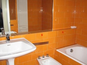 Kylpyhuone, jossa on pesuallas, peili ja kylpyamme.