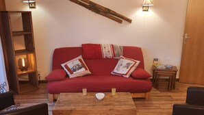 A cozy living room with a red sofa, wooden coffee table, and two wall-mounted lamps. - 4-bedroom apartment for 8 with garage, near shops and cable cars (Les Gets)