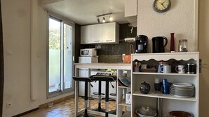 A compact kitchen with a microwave, coffee maker, and bar stools.