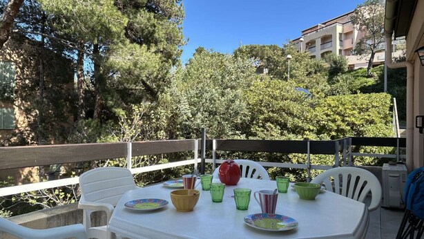 An outdoor patio with a white table set for dining, surrounded by white chairs.