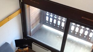 A small room with a window, a radiator, and a blue chair. - Spacious Studio Duplex in Les Gets - Sleeps 6, Garage, Near Slopes and Shops (Les Gets)