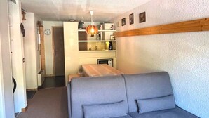 A compact living space with a sofa, a dining table, and a kitchenette. - Spacious Studio Duplex in Les Gets - Sleeps 6, Garage, Near Slopes and Shops (Les Gets)