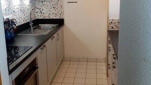 A compact kitchen with white cabinets, a black countertop, and a speckled backsplash.
