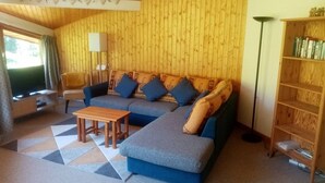 A cozy living room with a blue sofa, a wooden coffee table, and a bookshelf.