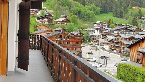 En balkong med utsikt över en by med traditionella trähus och en skylt som lyder ”Chamois d’Or”.