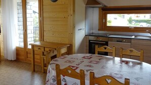 Ett kompakt kök med träskåp, en spis och ett fönster med utsikt över en gata.