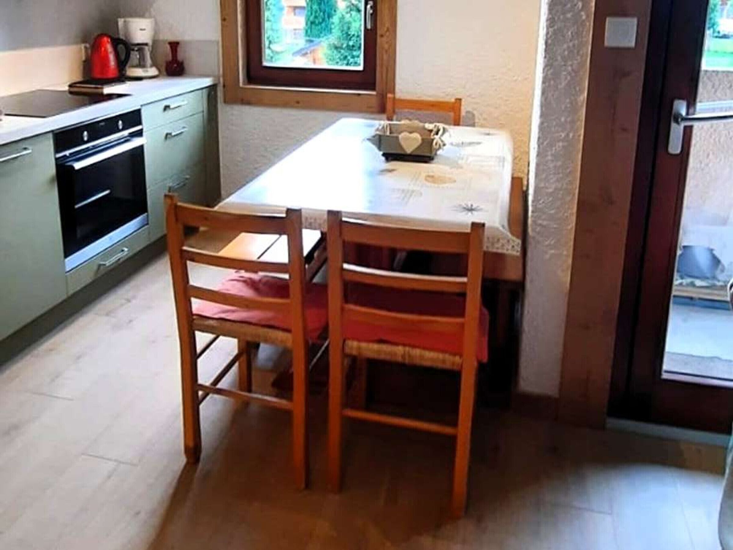 A compact kitchen with a dining table, chairs, and a window.