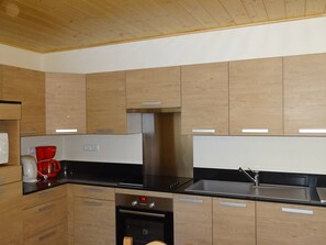 A modern kitchen with wooden cabinets, a stainless steel sink, and a built-in oven.