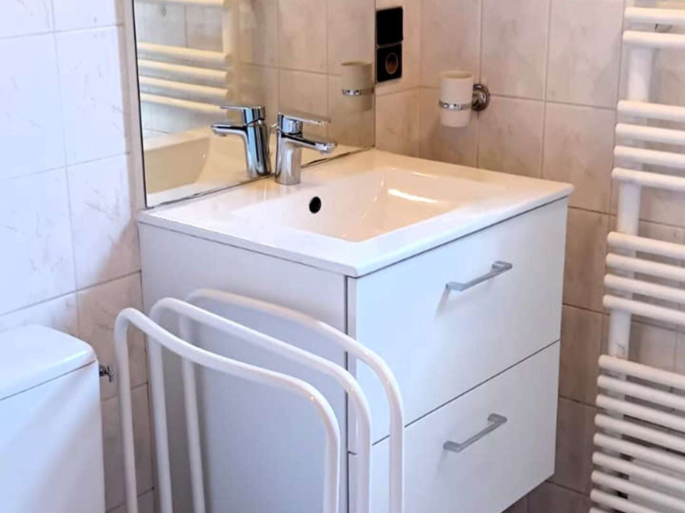 Een badkamer met een witte wastafel, spiegel en twee lades.