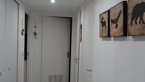 A hallway with a white door, a vent, and three wooden wall art pieces depicting animals.