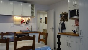 A compact kitchen with white cabinets, a microwave, and a small dining area with a table and chairs.