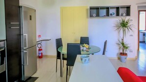 A modern kitchen with a white countertop, a built-in oven, and a stainless steel refrigerator. There is a dining table with chairs and a potted plant. - Apartment Binario 3, in Mariano Comense, WiFi. 20 meters from Northern Station. (Mariano Comense)