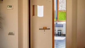 A hallway with a red chair, a light switch, and a thermostat on the wall. - Apartment Binario 3, in Mariano Comense, WiFi. 20 meters from Northern Station. (Mariano Comense)