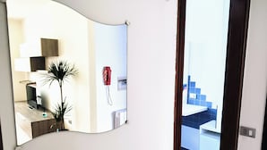 A modern kitchen with a curved mirror, a red telephone, and a plant. - Apartment Binario 3, in Mariano Comense, WiFi. 20 meters from Northern Station. (Mariano Comense)