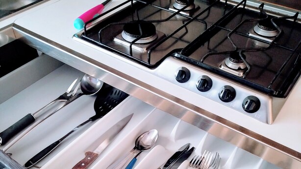 A kitchen with a stove and a drawer organizer containing various utensils. - Apartment Binario 3, in Mariano Comense, WiFi. 20 meters from Northern Station. (Mariano Comense)