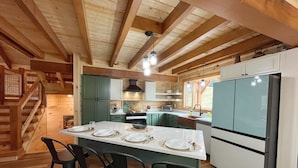 L’intérieur d’une cabane en bois comprend un îlot de cuisine, des tabourets de bar et un réfrigérateur.