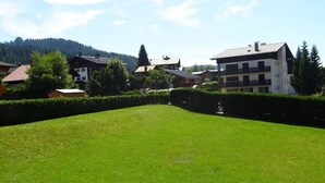 Zona verde y bien cuidada con seto, rodeada de edificios con una mezcla de arquitectura moderna y tradicional, con colinas al fondo.
