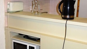 Una cocina con microondas, hervidor y tostadora sobre la encimera.