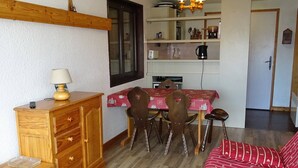 Una sala de estar acogedora con un aparador de madera, un sofá rojo y una mesa de comedor con sillas.